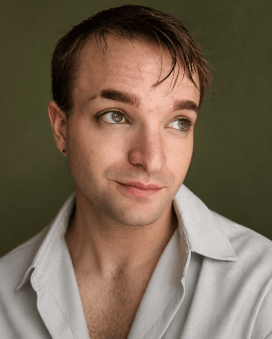 Against a starry nebula background is the headshot of an actor. They have intense eyes with dark eyeliner and are looking off to the left with a slight smile. Text reads Kian Burtin - Constantine  graphic       button    button  
