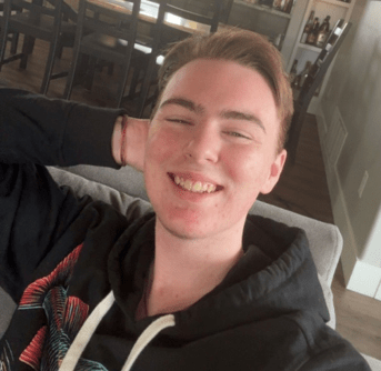 A man with short hair grins at the camera. He wears a black hoodie and has one hand behind his head. Text reads "Casey Flum - Questry"
