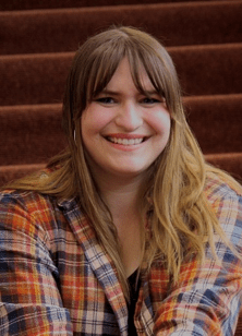 A headshot of a smiling woman with long golden brown hair and bangs. She wears a plaid shirt. Text reads Kaylee de Montigny Nora Alternate

